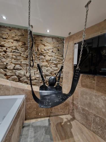 a swing in a room with a stone wall at L'éxperience LOVE ROOM in LʼÉtrat