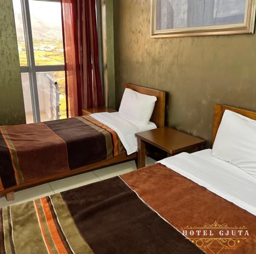 a hotel room with two beds and a window at HOTEL GJUTA in Tirana