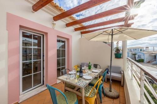 a balcony with a table and chairs and an umbrella at Casa Ensolarada in Budens