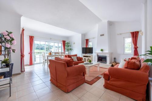 a living room with orange chairs and a fireplace at Casa Ensolarada in Budens