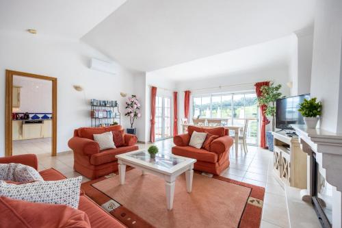 a living room with red chairs and a table at Casa Ensolarada in Budens