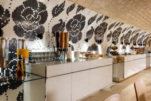a restaurant with a counter with a wall of food at Hotel Duminy-Vendome in Paris