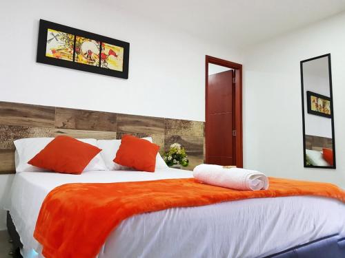 a bedroom with a large bed with orange and white pillows at Hotel Don Jose in Ciénaga