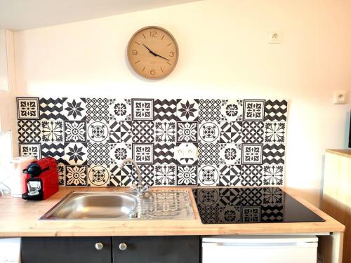 une cuisine avec un évier et une horloge murale dans l'établissement Studio rue Leopold bourg, à Épinal