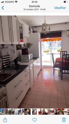 eine Küche mit weißen Schränken sowie einem Tisch und Stühlen in der Unterkunft Bel appartement très bien situé avec place de parking in Marseille