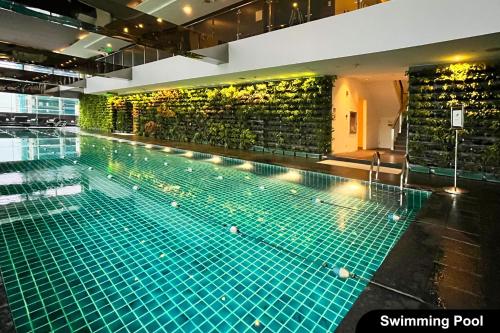 une grande piscine avec un mur vert dans l'établissement the Gramercy Residences, à Manille