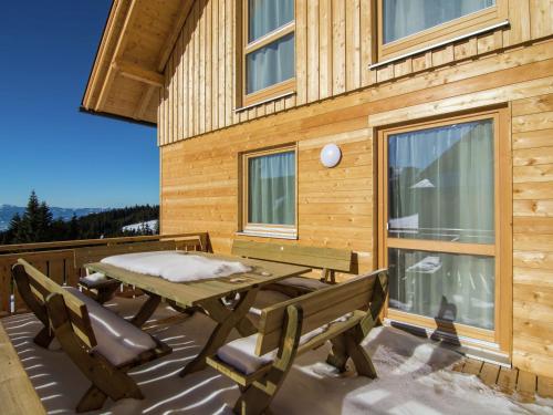 a picnic table and benches on the deck of a cabin at Chalet in Carinthia with Sauna near Ski Slopes in Weinebene
