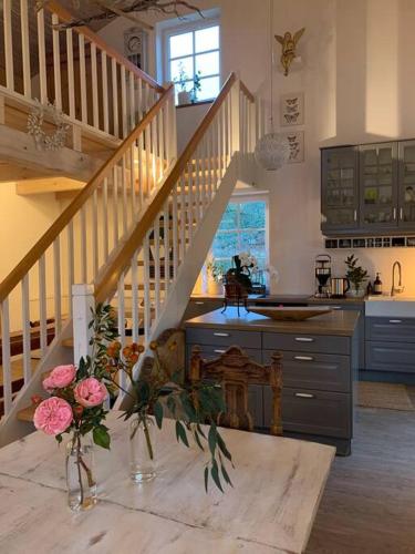 a kitchen with a staircase and a table with flowers at Landhaus „Blattgold“ in Lohme