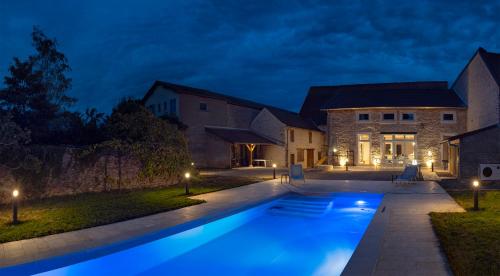 a swimming pool in front of a house at night at Gîte Bellene Villa de vos Rêves in Beaune