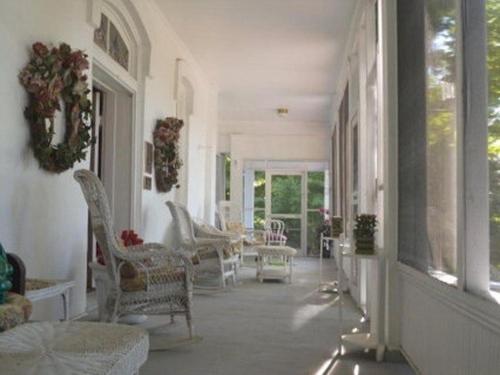 Franklin Terrace Bed and Breakfast في فرانكلين: غرفة معيشة مع كراسي بيضاء وشرفة