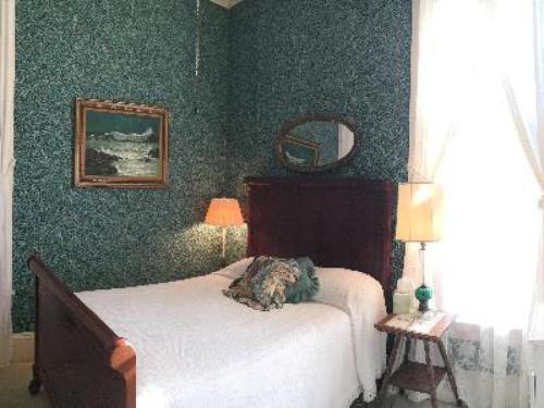 ein Schlafzimmer mit einem Bett und einer grünen Wand in der Unterkunft Franklin Terrace Bed and Breakfast in Franklin