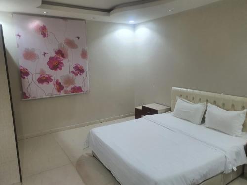 a bedroom with a white bed and a painting on the wall at برج الياسمين 2 in Riyadh