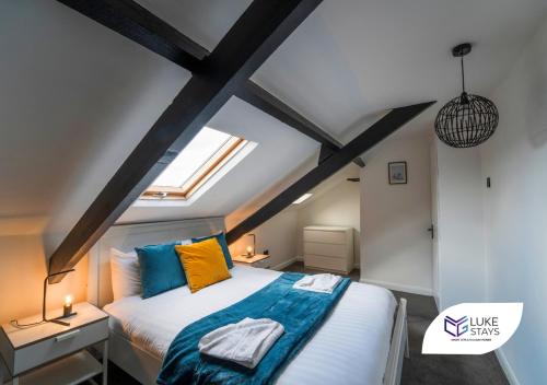 ein Schlafzimmer mit einem großen Bett mit blauen und orangefarbenen Kissen in der Unterkunft Luke Stays - Brighton Road in Gateshead