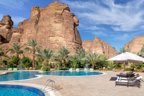 um resort com uma piscina em frente a uma formação rochosa em Shaden Resort em Al-ʿUla