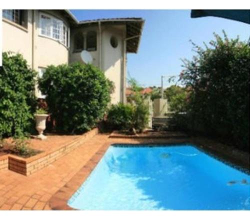 a large blue swimming pool in front of a house at Rehoboth Guesthouse in Durban