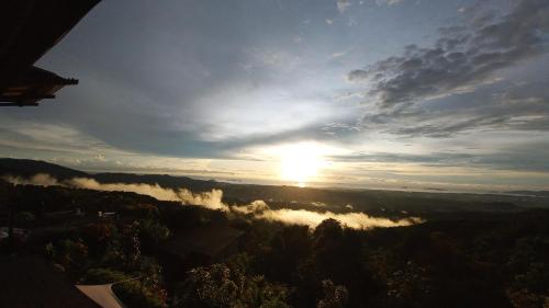 a view of the sun rising over a valley with trees at Sinurambi Cottage Rental in Penampang