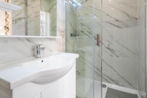 une salle de bain blanche avec un lavabo et une douche dans l'établissement Modern apartment - 1BR-4P - Parc de Belleville, à Paris
