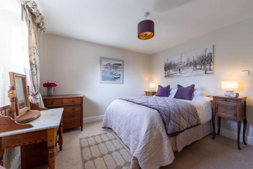 a bedroom with a bed and a desk with two lamps at Leatside Cottage in Dulverton