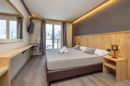 a bedroom with a large bed and a desk at Hotel Piandineve in Passo del Tonale