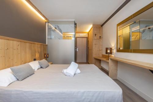 a bedroom with a large bed with white sheets at Hotel Piandineve in Passo del Tonale
