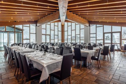 a banquet hall with tables and chairs and windows at Hotel Piandineve in Passo del Tonale