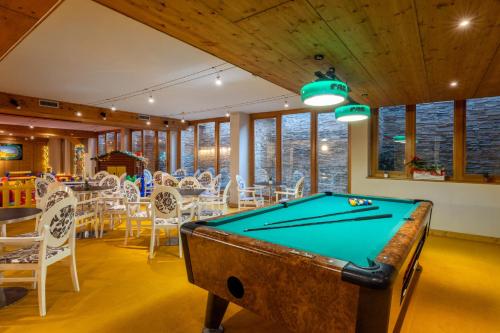 a pool table in a room with tables and chairs at Hotel Piandineve in Passo del Tonale
