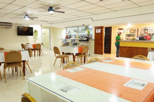 a restaurant with tables and chairs and a person in a kitchen at Hotel Interamericano in Aguadulce