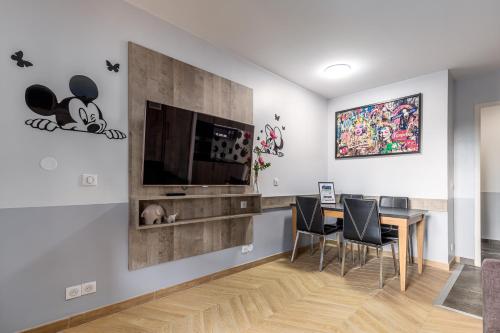 a dining room with a table and a television on a wall at Disneyland Appartements familial avec piscine intérieur chauffé, parking gratuit A 5 minutes des parcs in Serris