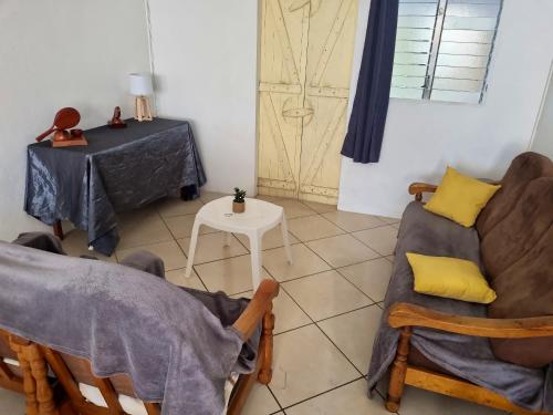 ein Wohnzimmer mit einem Tisch und einem Sofa in der Unterkunft Maison de 2 chambres avec jardin clos et wifi a Le Robert a 1 km de la plage in Le Robert