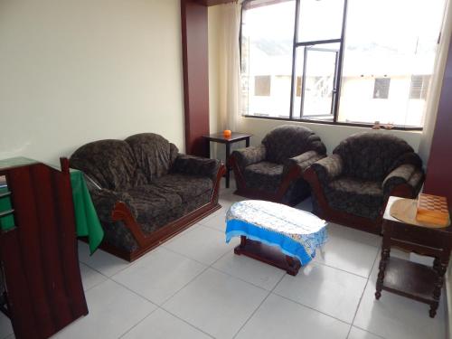 a living room with three chairs and a table at Comodo y centrico in Ambato