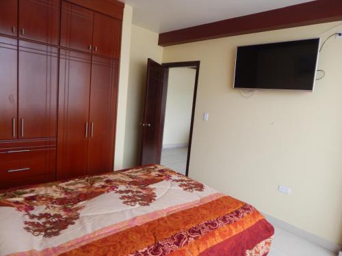a bedroom with a bed and a flat screen tv at Comodo y centrico in Ambato