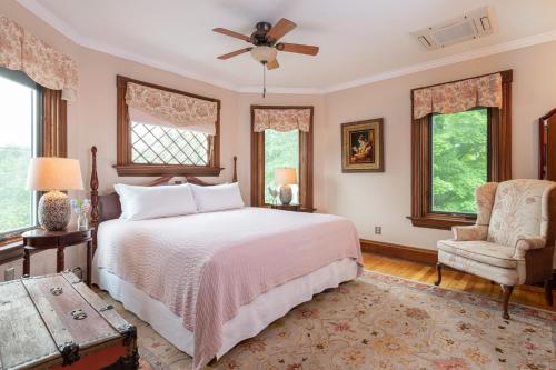 Schlafzimmer mit einem Bett, einem Stuhl und Fenstern in der Unterkunft Sinclair Inn Bed & Breakfast in Jericho
