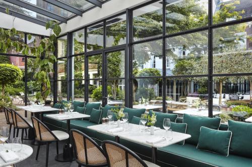 un restaurante con mesas, sillas y ventanas en Pulitzer Amsterdam, en Ámsterdam