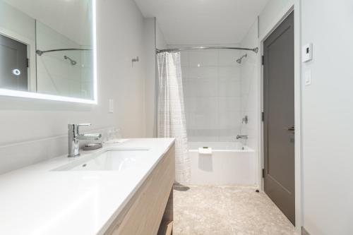 y baño blanco con lavabo y ducha. en Suites du Lac Moore, en Mont-Tremblant