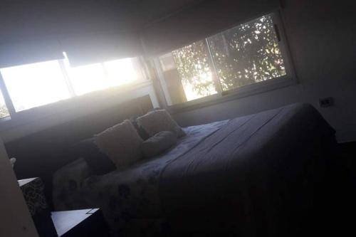 1 dormitorio con 1 cama con 2 almohadas y 2 ventanas en Hermosa casa en Country en Santo Tomé