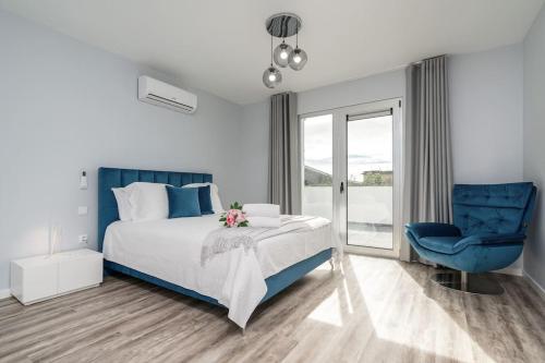 um quarto com uma cama e uma cadeira azul em Casa Alan by Rent2u, Lda em Arco da Calheta