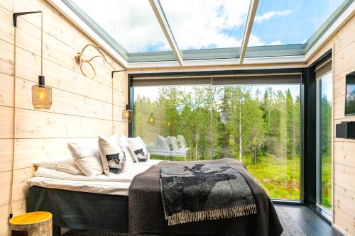 a bedroom in a tiny house with a large window at Kuuru Tunturilaakso by Kide Hotel in Syöte