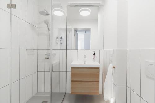 a white bathroom with a sink and a shower at PLANTONIA Aparthotel in Krakow