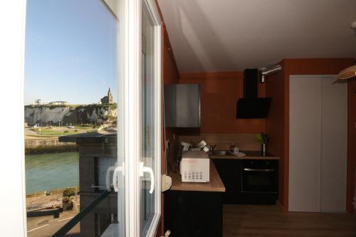 une cuisine avec une fenêtre offrant une vue sur la ville dans l'établissement La Jetée Appartement Vue Mer, à Dieppe