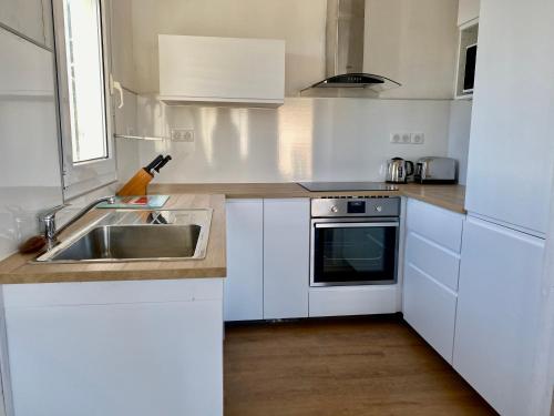 a white kitchen with a sink and a stove at Chalet L' Aliénor in Gruissan