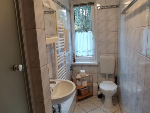 ein Bad mit einem Waschbecken, einem WC und einem Fenster in der Unterkunft Kleine Ferienwohnung am Strand in Kühlungsborn in Kühlungsborn