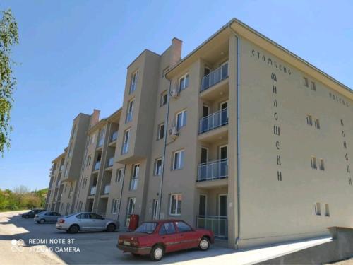 een groot appartementencomplex met een rode auto op een parkeerplaats bij Studio Star in Soko Banja