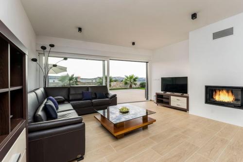 a living room with a black couch and a fireplace at Villa Danijela, brand new villa with private pool in Stara Novalja