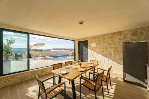 uma sala de jantar com mesa e cadeiras e uma grande janela em Villa Danijela, brand new villa with private pool em Stara Novalja