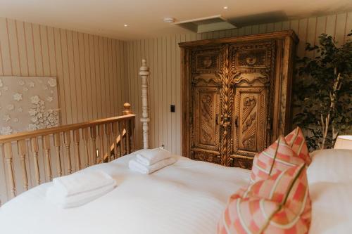 a bed with white sheets and a large wooden door at The Tempus at Charlton Hall Estate in Alnwick