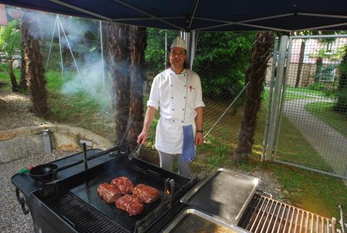 a man standing next to a grill with meat at Continental Parkhotel in Lugano