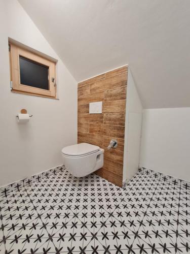 a bathroom with a toilet and a black and white tile floor at Apartmán Konírna in Harrachov