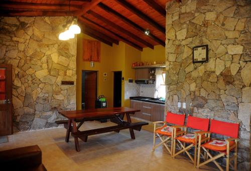 cocina con mesa, sillas y pared de piedra en Terrazas al Champaqui en Villa Yacanto