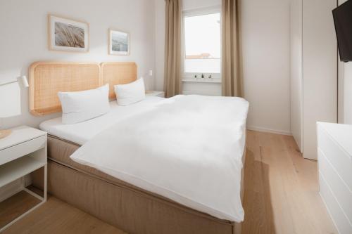 ein Schlafzimmer mit einem großen Bett mit weißer Bettwäsche in der Unterkunft Kapkieker in Norderney