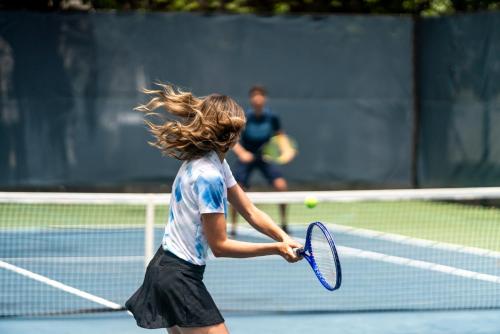 a young girl holding a tennis racket on a tennis court at Fairmont El San Juan Hotel in San Juan
